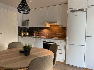 uma cozinha com uma mesa de madeira e um frigorífico branco em Beautiful apartment - own parking space included em Vantaa