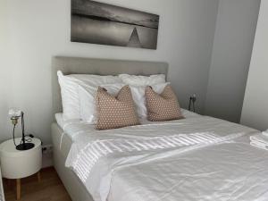 um quarto com uma cama branca com almofadas em Beautiful apartment - own parking space included em Vantaa