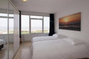 Dos camas en una habitación con dos ventanas. en The Lookout, en Egmond aan Zee