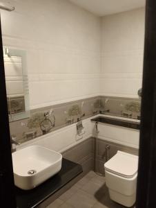 a bathroom with a white sink and a toilet at Hotel Samudyatha Inn And Suites in Kundapur