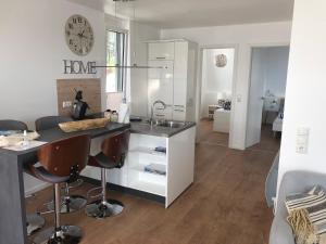 Una cocina con fregadero y una encimera con sillas. en Schwimmendes Ferienhaus Heimathafen, en Großenbrode