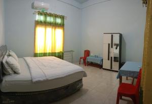 Schlafzimmer mit einem Bett, einem Tisch und einem Kühlschrank in der Unterkunft Tangkoko Gallery Guest House and Resto in Rinondoran