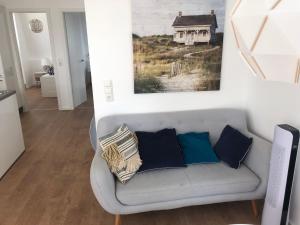 uma sala de estar com um sofá cinzento com almofadas em Schwimmendes Ferienhaus Heimathafen em Großenbrode