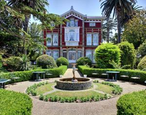 a red house with a fountain in front of a garden at Villa La Argentina in Luarca