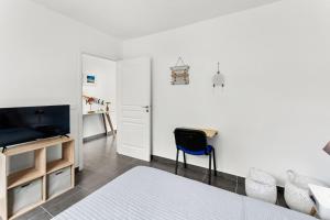 ein Wohnzimmer mit einem TV und einem blauen Stuhl in der Unterkunft Le Cosmopolitain_ Appart 4/5p terrasse piscine in Cul de Sac