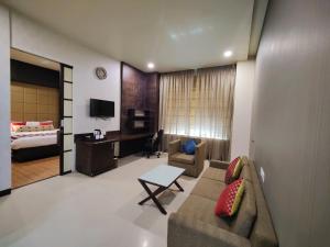 a living room with a couch and a bedroom at Regenta Central Grand Exotica in Pune