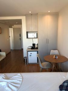 a room with a bed and a table and a kitchen at Flat apart-hotel pelinca in Campos dos Goytacazes