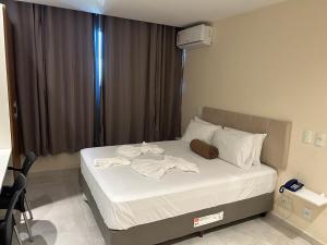 een slaapkamer met een bed met witte lakens bij Flat apart-hotel pelinca in Campos dos Goytacazes