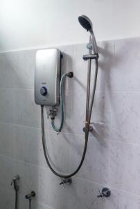 a shower head on a wall in a bathroom at Homestay Cikgu Alif in Wakaf Baharu