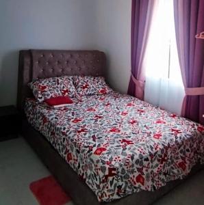 una camera con un letto e un piumone rosso e bianco di Homestay Cikgu Alif a Wakaf Baharu