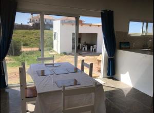 a dining room with a table and chairs and a kitchen at Casa de Coral in Punta Del Diablo