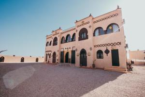 ein großes, hellbraunes Gebäude mit schwarzen Türen und Fenstern in der Unterkunft Traditional Riad Merzouga Dunes in Merzouga