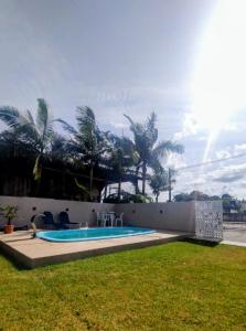 a swimming pool in a yard with palm trees at Férias Perfeitas, Praia e Piscina in Itapoa