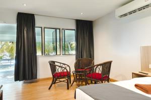 een slaapkamer met 2 stoelen, een bed en ramen bij Pangkor Sandy Beach Resort in Pangkor