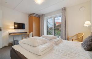 a bedroom with a large white bed with a window at Nice Apartment In Allinge With Wifi in Sandvig