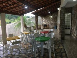 eine Terrasse mit Tischen und Stühlen in einem Steingebäude in der Unterkunft Casa para temporada e hospedagem in Juiz de Fora