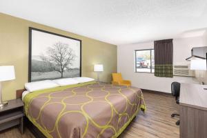 a hotel room with a bed and a desk and a window at Super 8 by Wyndham Johnson City in Johnson City
