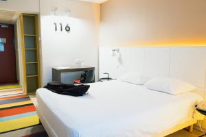 a bedroom with a white bed with a black bag on it at ibis Styles Lyon Sud Vienne in Chasse-sur-Rhône