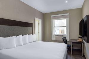 a hotel room with a large white bed and a window at Super 8 by Wyndham San Francisco/Union Square Area in San Francisco