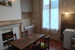 a kitchen with a dining room table and a fireplace at Appartement rez de jardin in La Chartre-sur-le-Loir