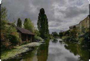 un río con edificios a su lado en Appartement rez de jardin, en La Chartre-sur-le-Loir