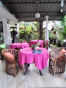 uma sala de jantar com mesas e cadeiras cor-de-rosa em Rock Cascade tourist home em Pollonaruva