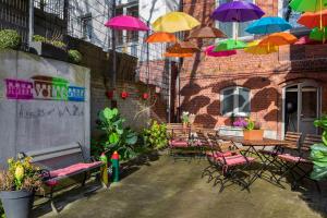 a patio with tables and chairs and colorful umbrellas at Hotel Volksschule in Hamburg +35 photos