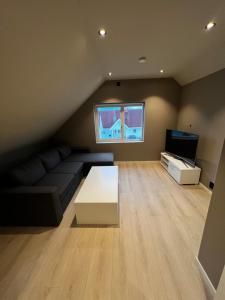 a living room with a couch and a tv at Nytt hus i rolig familiestrøk in Verdal