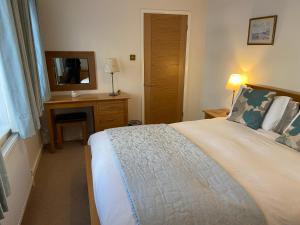 a bedroom with a bed and a desk and a mirror at The Bothy in Lyndhurst