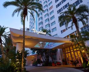 un hotel con palmeras frente a un edificio en The Confidante Miami Beach, part of Hyatt, en Miami Beach