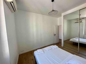 Habitación blanca con cama y espejo en Agréable deux pièces spacieux / climatisé / balcon, en Niza