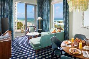 a room with a table and chairs and a view of the ocean at The Confidante Miami Beach, part of Hyatt in Miami Beach