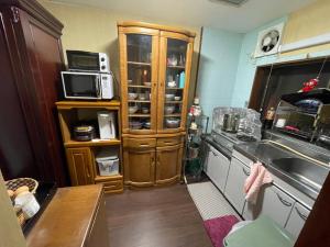 eine Küche mit einer Spüle und einer Mikrowelle in der Unterkunft AnNam Stay TOYONAKA in Toyonaka