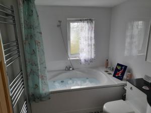 y baño con bañera y ventana. en Grovewood House Retreat en Kirkbean