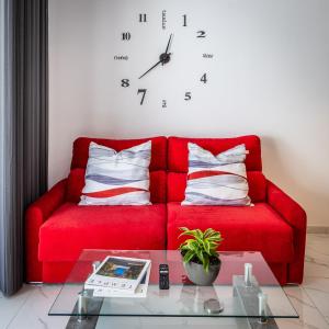 a red couch with pillows and a clock on a wall at Urban Downtown Den in St Julians in St. Julianʼs