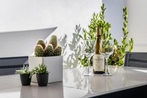 a bottle of wine and glasses on a table with plants at Urban Downtown Den in St Julians in St Julian's