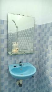 ein Badezimmer mit einem blauen Waschbecken und einem Spiegel in der Unterkunft Tangkoko Gallery Guest House and Resto in Rinondoran