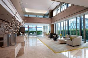 a lobby with couches and chairs in a building at Humble House Taipei, Curio Collection by Hilton in Taipei
