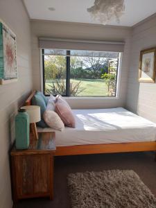 a bed in a room with a window at Garden Oasis in the heart of Pāpāmoa in Tauranga