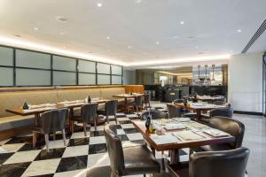 un ristorante con tavoli e sedie in legno e pavimento a scacchi di The Hotel Galleria Jeddah, Curio Collection by Hilton a Gedda