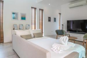 a living room with a white couch and a tv at Vimaan Vilai - Secluded Pool Villa in Amphoe Koksamui