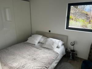 a bedroom with a bed with white sheets and a window at Le nid d'aigle in Chamoson