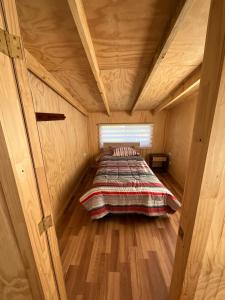 1 dormitorio con 1 cama en una habitación de madera en Cabañas Maldonado, en Hornopirén