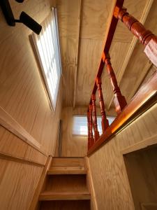 una escalera de madera en una casa pequeña con ventana en Cabañas Maldonado, en Hornopirén