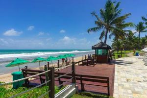 uma praia com mesas e guarda-sóis verdes e o oceano em Flat Beach Class Muro Alto - Porto de Galinhas 02 Quartos em Porto de Galinhas