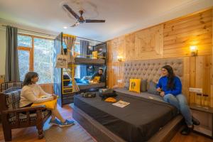 Dos mujeres sentadas en una cama en un dormitorio en The Hosteller Manali, Old Manali, en Manali