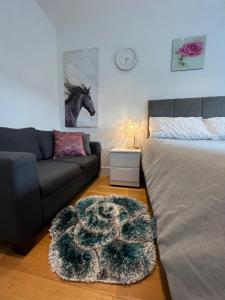 a bedroom with a bed and a couch and a horse picture at Modern 1 bedroom apartment in the center of Croydon in Croydon