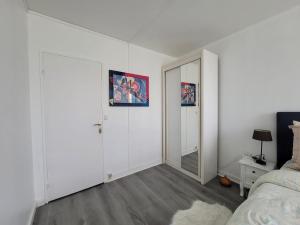 Cette chambre blanche comprend un lit et un miroir. dans l'établissement Charmante chambre chez l'habitant, à Ivry-sur-Seine
