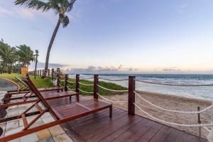 a wooden deck with two benches on the beach at Flat Beach Class Muro Alto - Porto de Galinhas 02 Quartos in Porto De Galinhas