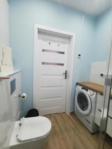 a bathroom with a toilet and a washing machine at Apartament SKALNIAK in Kudowa-Zdrój